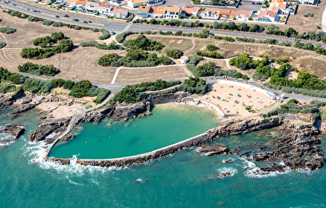 Le bassin Dombret vu du ciel : une piscine d'eau de mer entre les rochers, au bord de l'océan