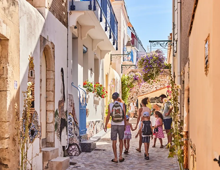 Une famille se promène dans une ruelle de l'île Penotte aux façades ornées de mosaïques