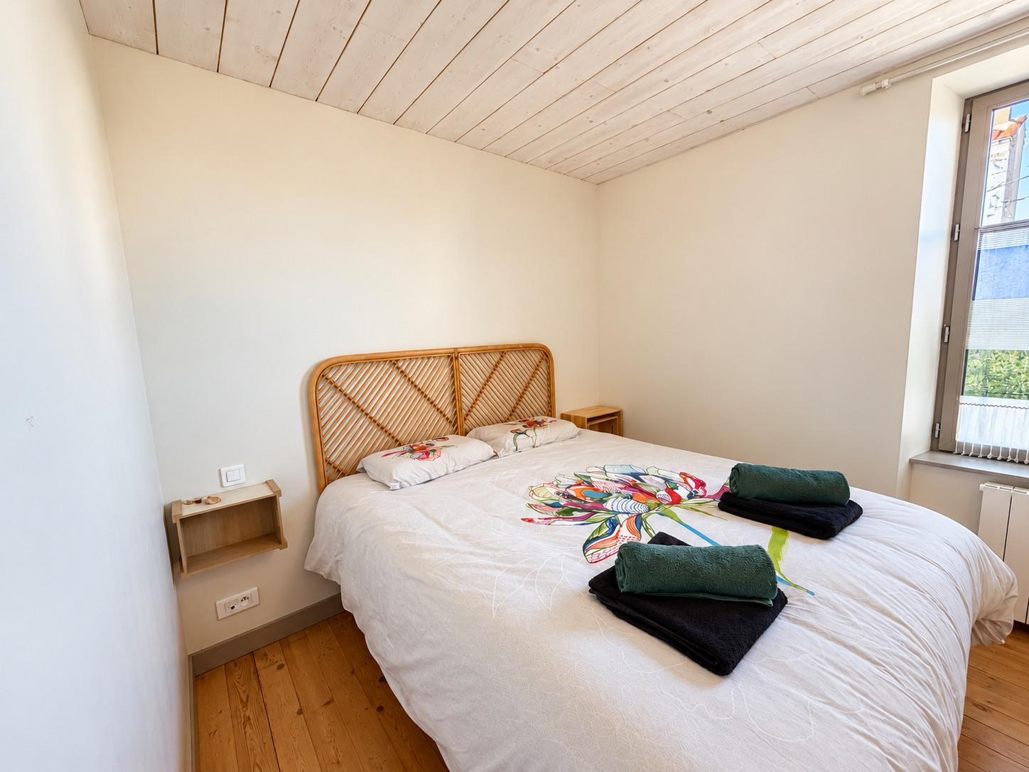 Chambre lumineuse avec tête de lit en rotin et parquet en bois