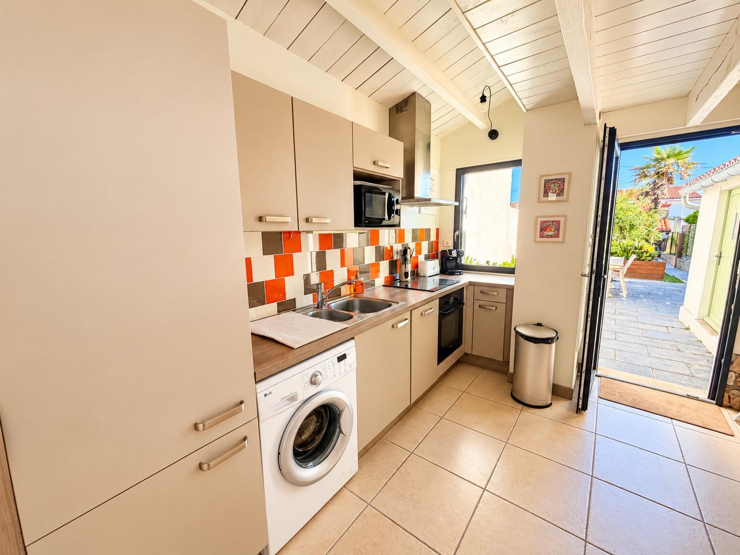 La cuisine ouverte de la maison principale, porte-fenêtre ouverte sur la terrasse