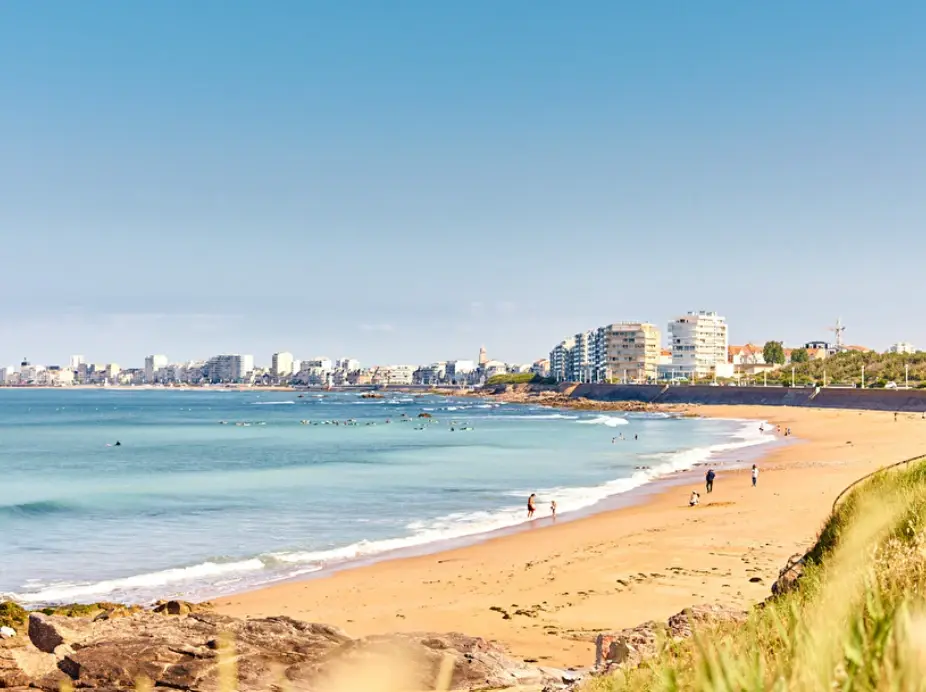 La plage de Tanchet et ses surfeurs, la ville des Sables-d'Olonne à l'horizon